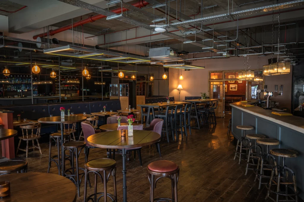 Spacious interior of The Hill with the bar counter, high tables and stools, banquette seating and warm pendant lighting.