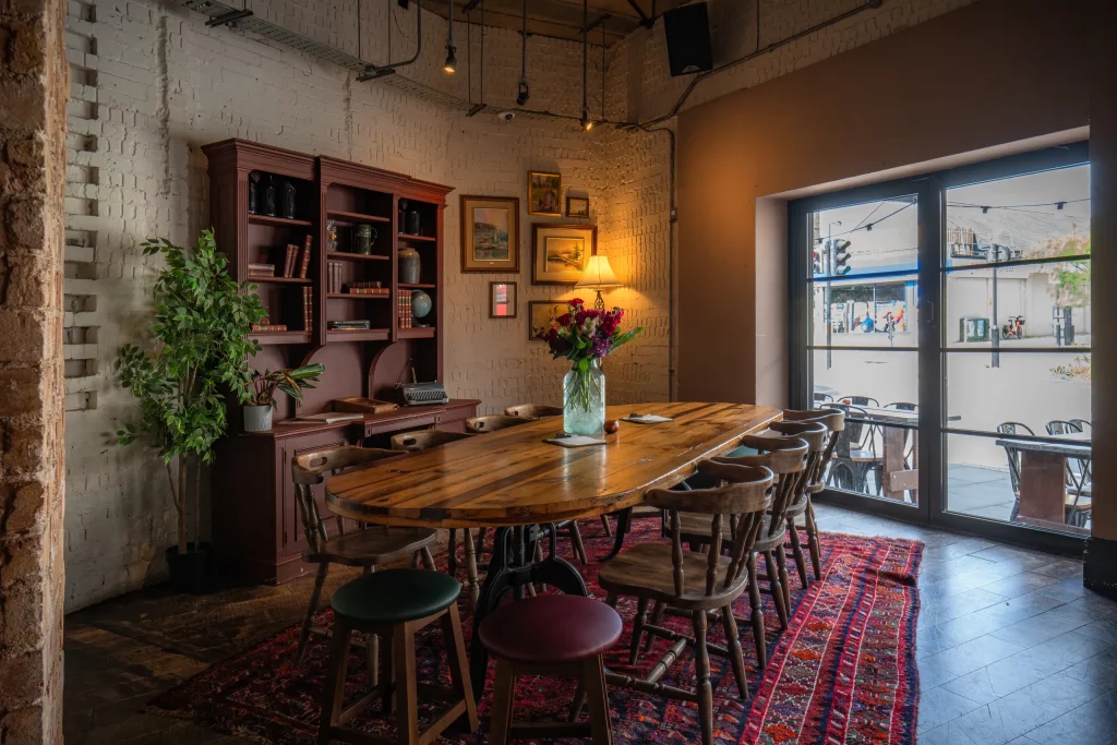 Intimate dining room with white painted brick, a long communal table and glazed doors opening to the terrace.